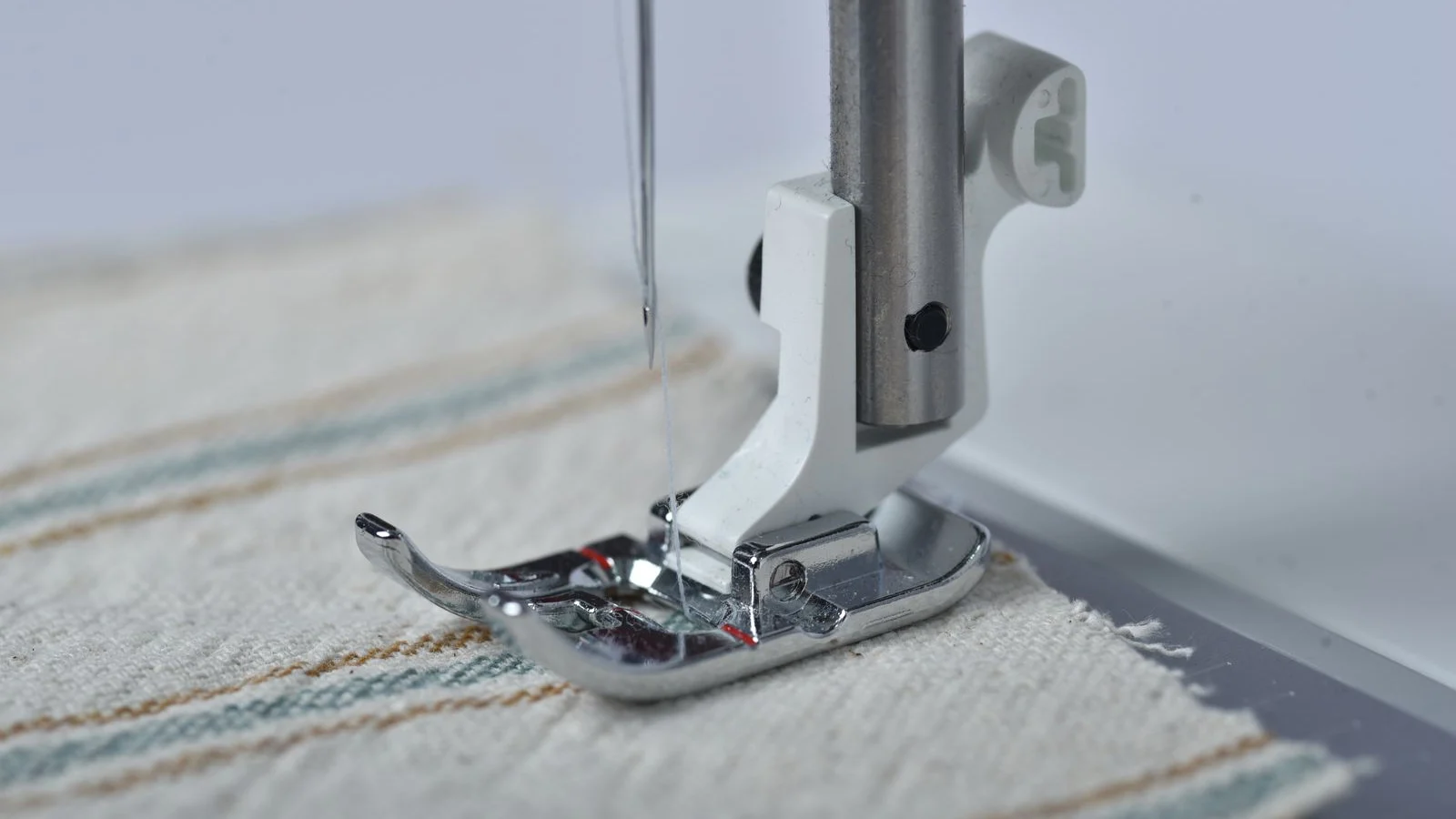 Sewing machine presser foot on fabric — close-up